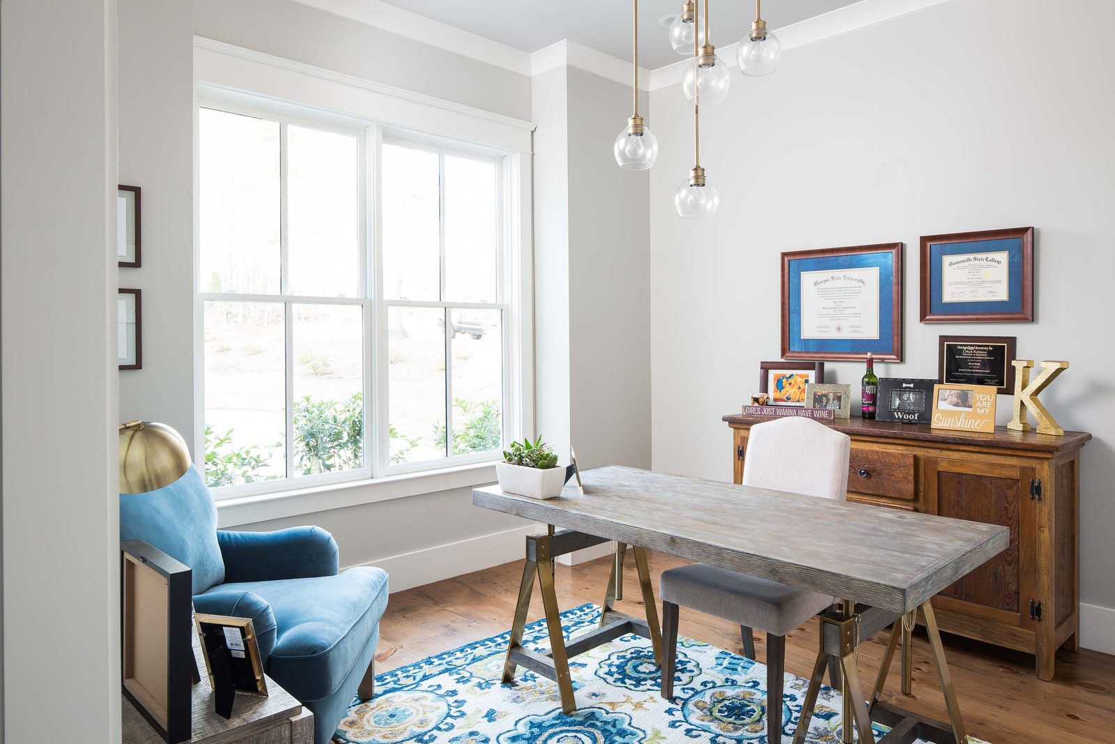 Home office with a wall of windows and framed art — Austin Garner Rd, custom home built by Ironwood Construction Group