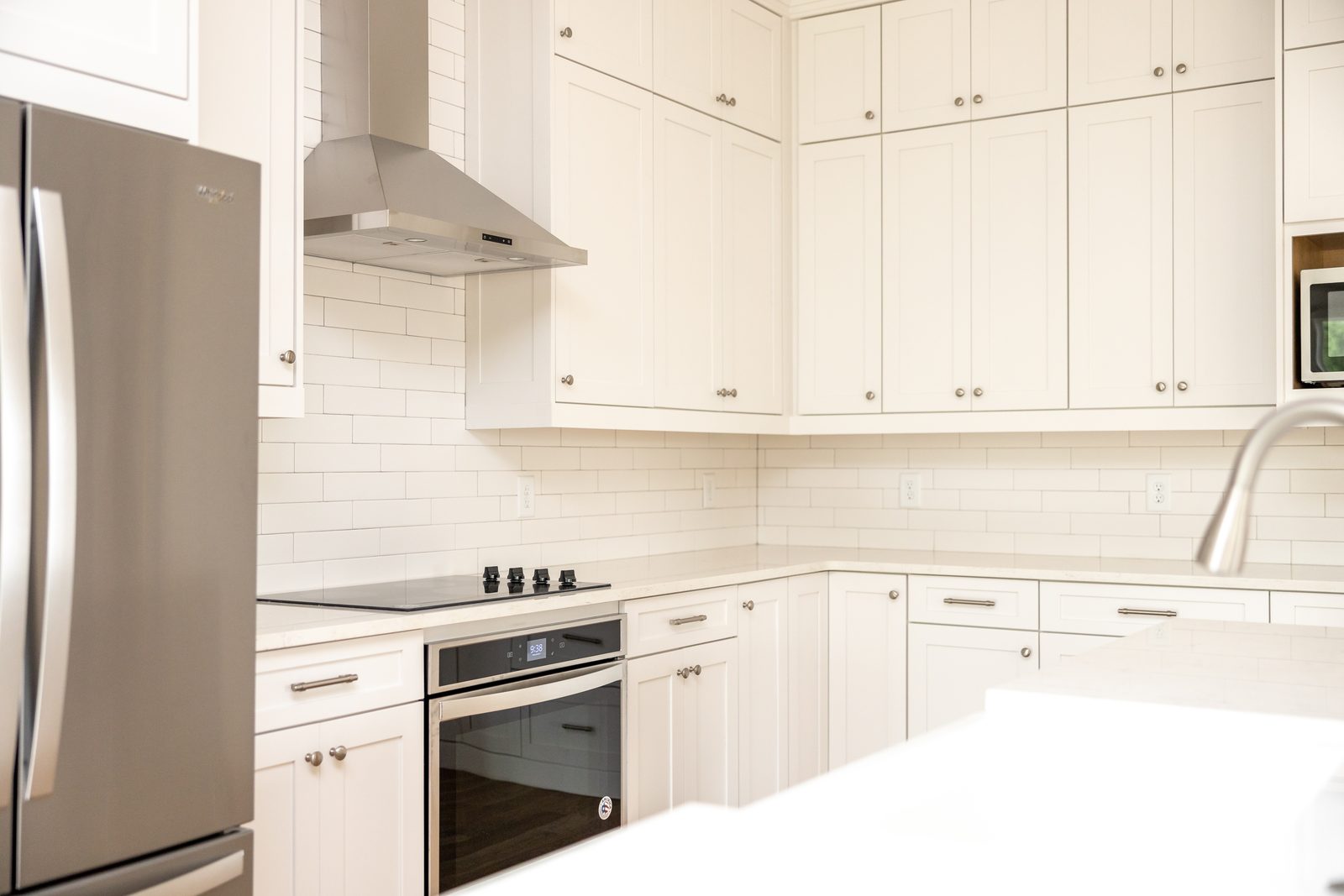 Kitchen corner with stainless refrigerator, wall oven and hood — Shadburn Ferry, custom home built by Ironwood Construction Group in Buford, Georgia