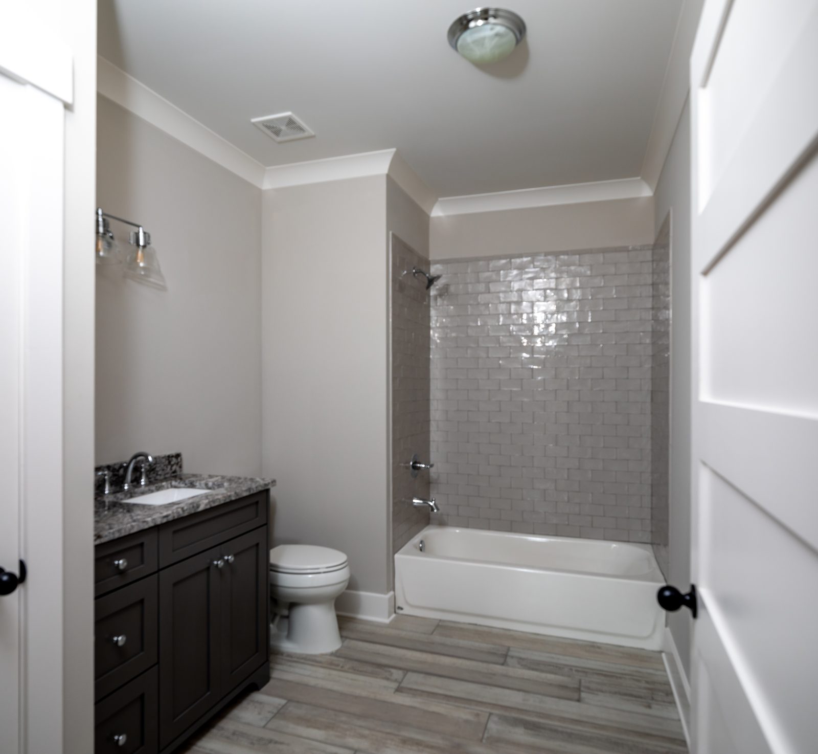 Secondary bath with dark vanity and tiled tub surround — Shadburn Ferry, custom home built by Ironwood Construction Group in Buford, Georgia